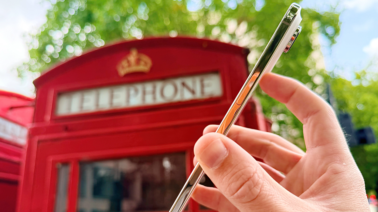 hand holding the new iPhone Air in front of a red phone box in London