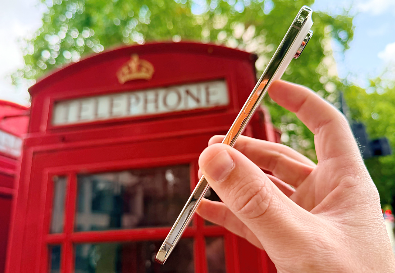 hand holding the new iPhone Air in front of a red phone box in London