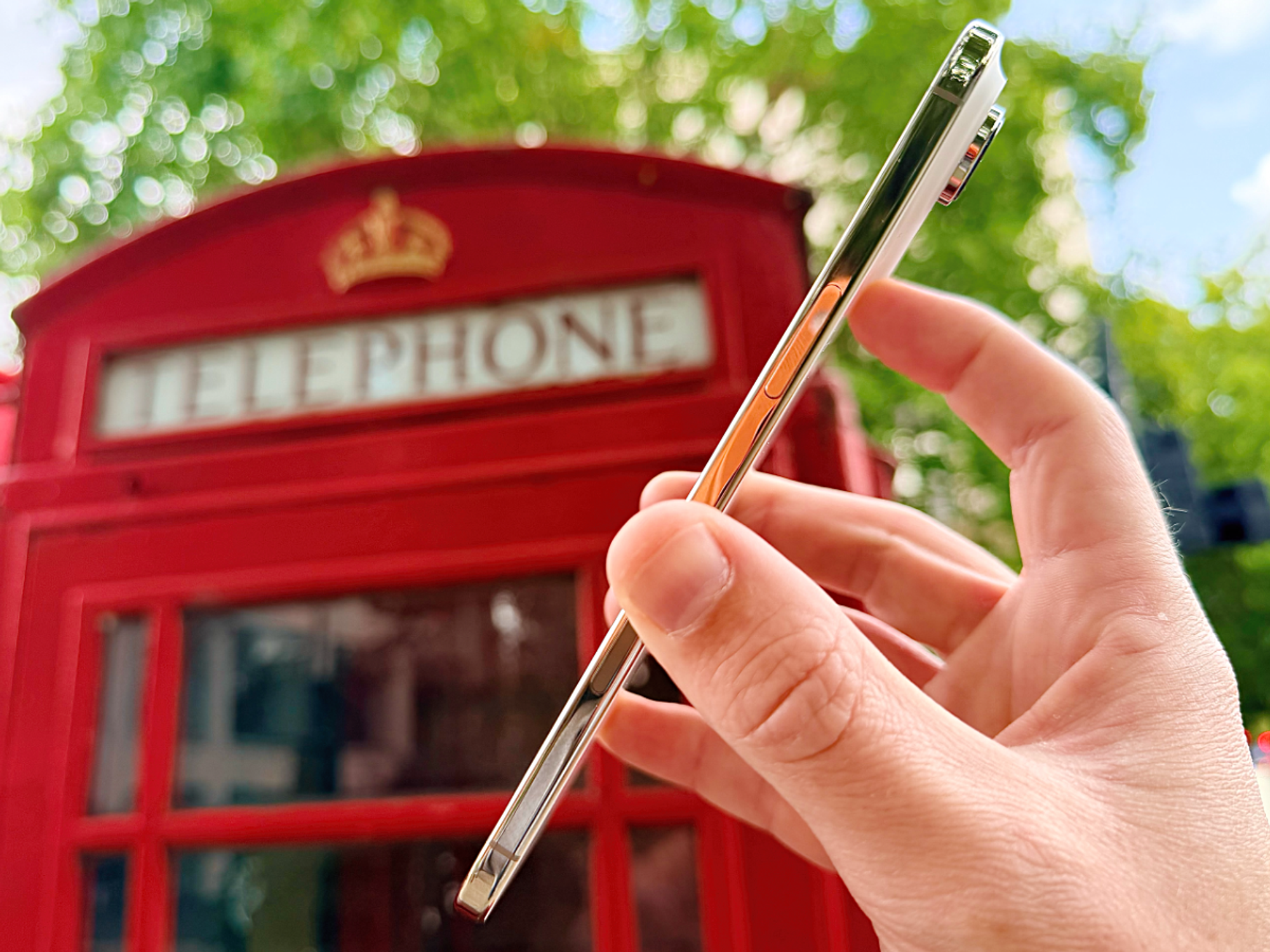 hand holding the new iPhone Air in front of a red phone box in London