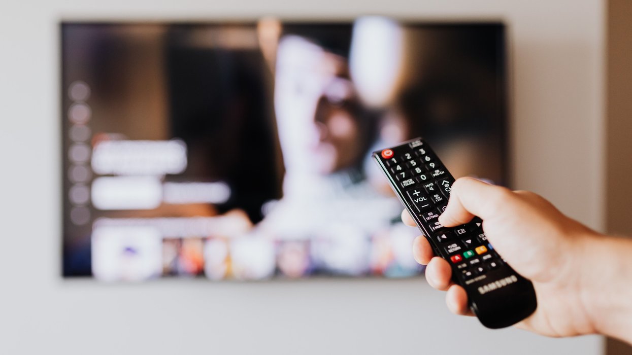 Hand holding TV remote in front of TV