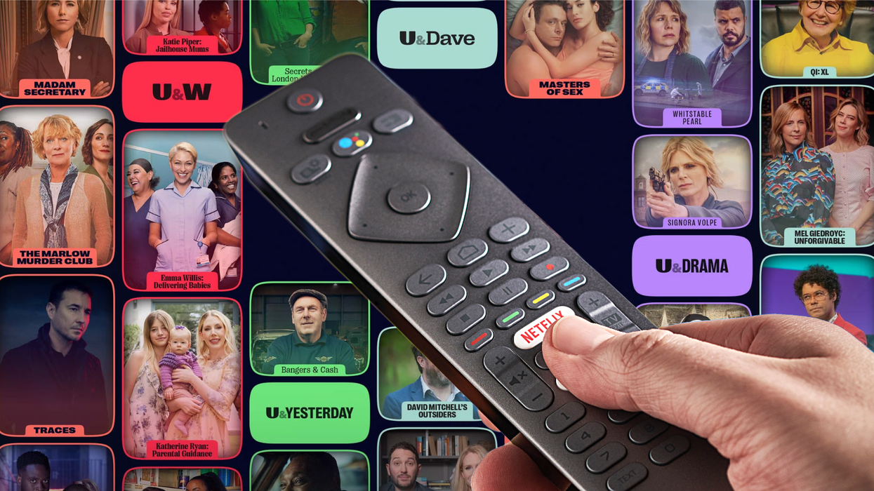 hand holds a TV remote control with a selection of UKTV streaming shows in the background