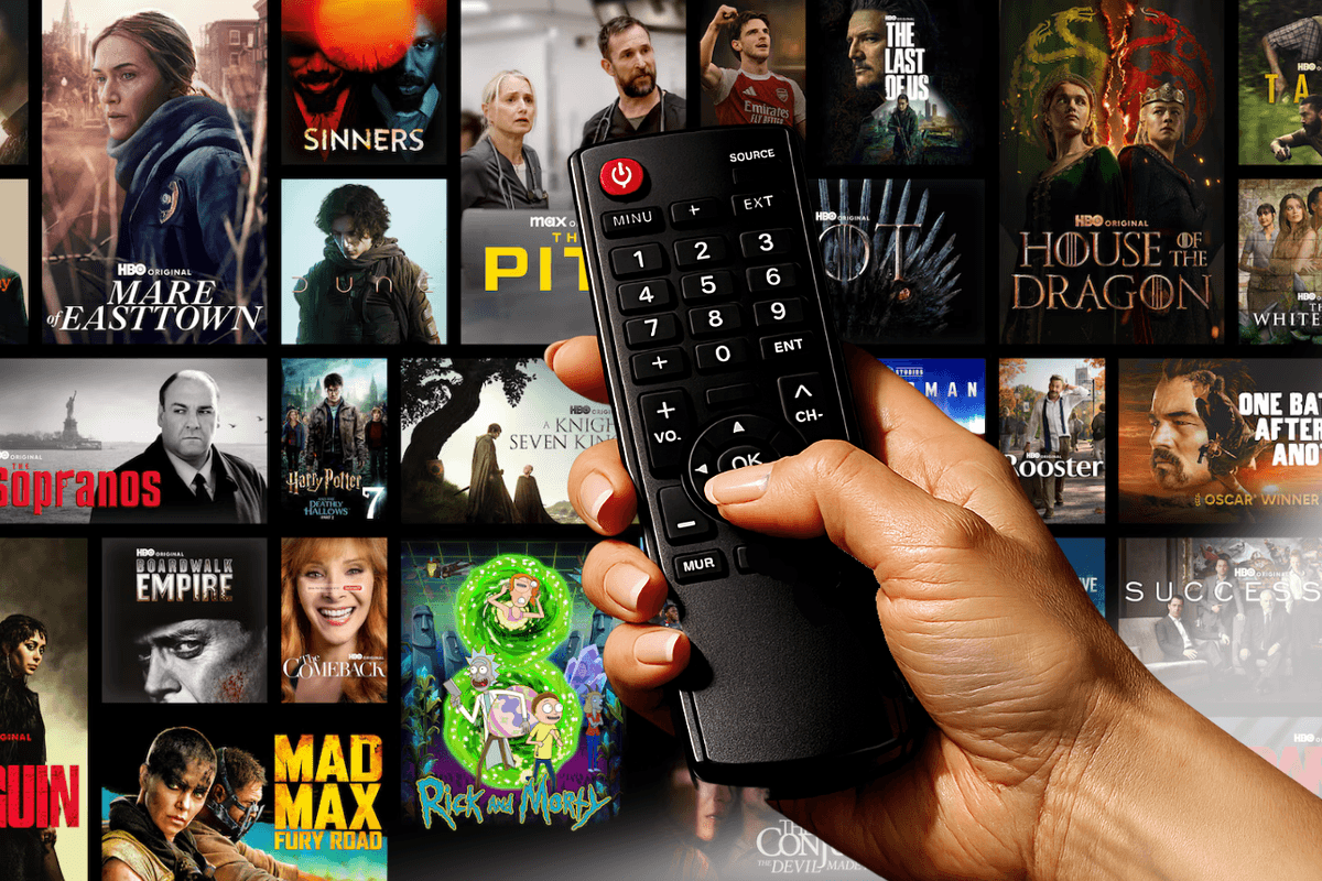 hand holds a tv remote with a selection from the HBO Max catalogue in the background
