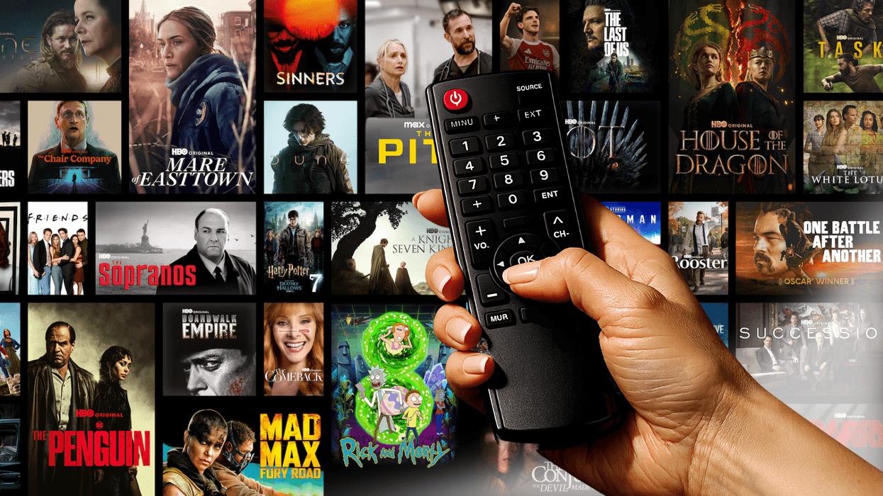 hand holds a tv remote with a selection from the HBO Max catalogue in the background