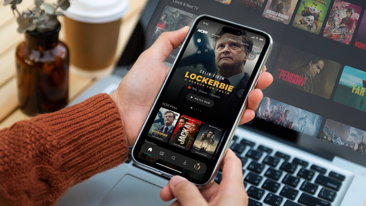 hand holds an iphone with the redesigned NOW interface shown on-screen