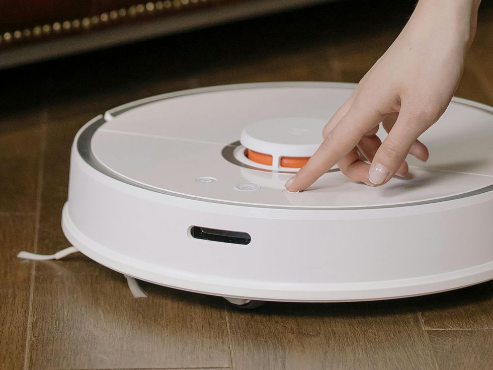 Hand turning on robot vacuum cleaner