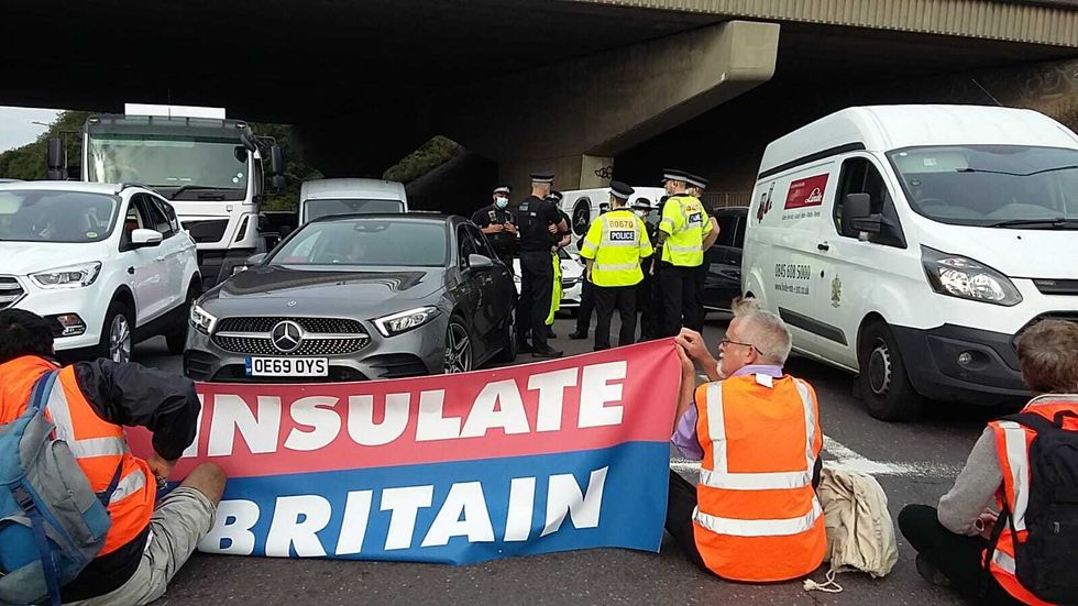 Handout photo issued by Insulate Britain of police speaking to one another as protesters block an M25 junction.