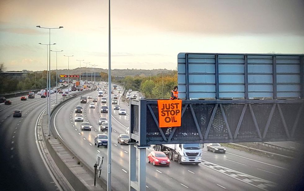 Handout photo issued by Just Stop Oil of an activist on a overhead gantry on the M25. Just Stop Oil said around 10 of its supporters climbed onto overhead gantries in %22multiple locations%22 on the M25 from 6.30am on Wednesday, in what is the third consecutive day of protests on the UK's busiest motorway. Issue date: Wednesday November 9, 2022.