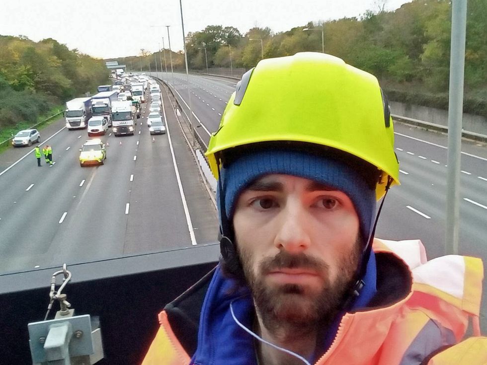 Handout photo issued by Just Stop Oil of an activist on a overhead gantry on the M25 which has been closed by police due to ongoing protests from the group. Just Stop Oil supporters are protesting on the M25 for the fourth consecutive day. Surrey Police said officers are dealing with activists who climbed a gantry at Junction 8 of the UK's busiest motorway. The road is closed anti-clockwise. Essex Police said it arrested a woman attempting to climb a gantry around 1.5 miles from Junction 28 clockwise. The force said: %22One lane was closed for a short time as officers responded to the situation. Issue date: Thursday November 10, 2022.