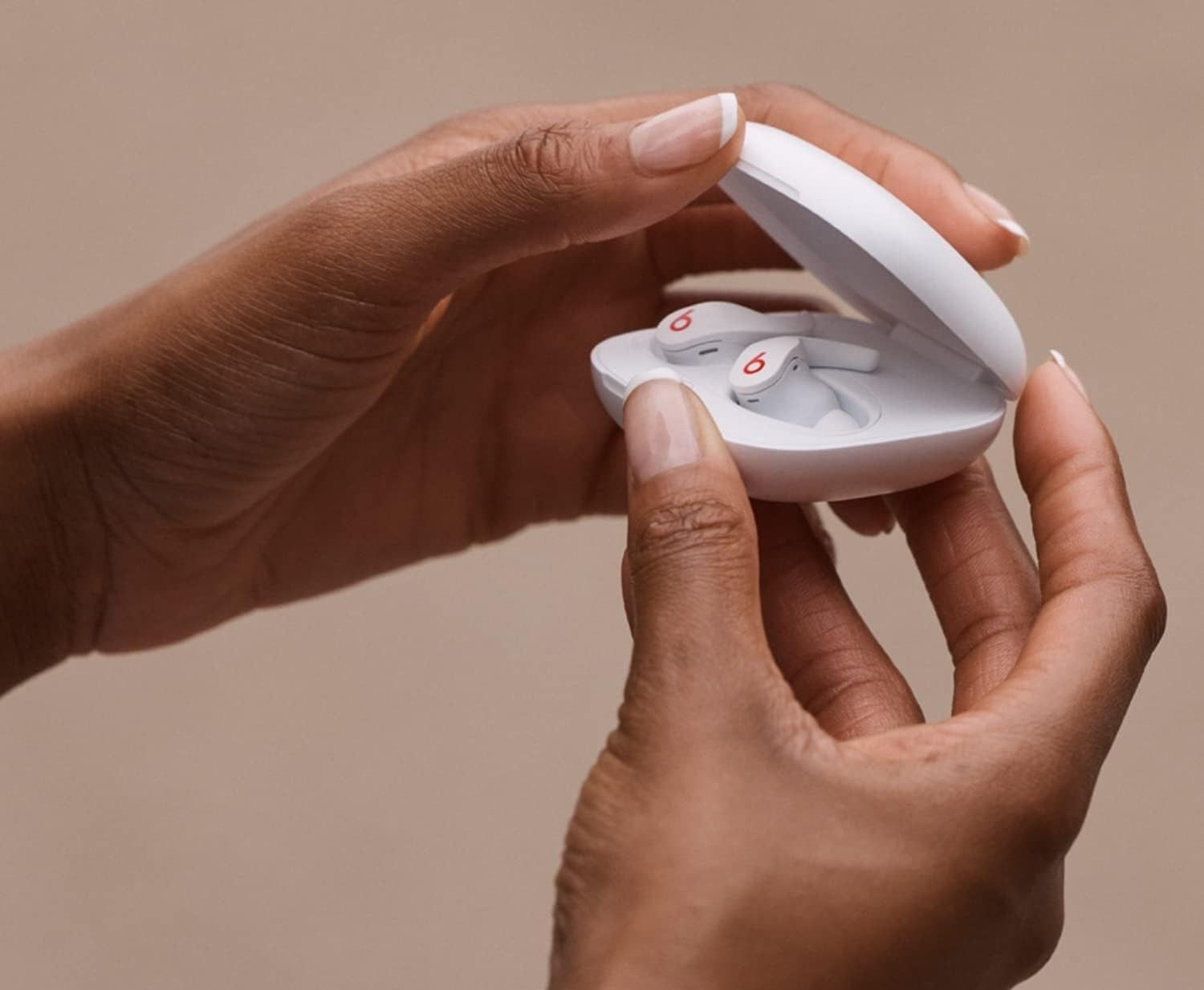 hands open the beats fit pro earbuds in a charging carry case