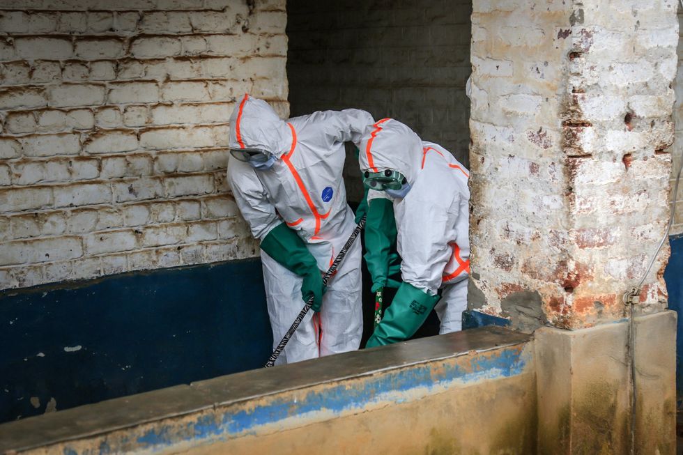 Health workers wearing protective equipment disinfect the isolation area for Ebola patients
