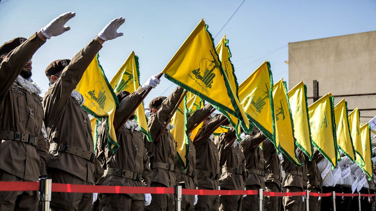Hezbollah members salute and raise the group's yellow flags