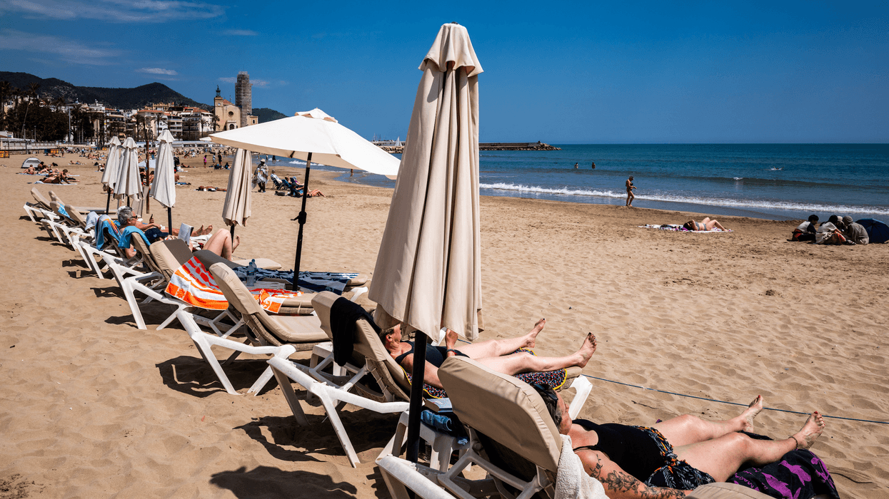Holiday makers enjoy sun loungers on beach