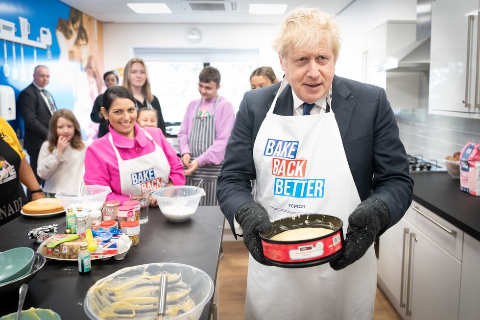 Home Secretary Priti Patel looks on as Prime Minister Boris Johnson tries his hand at baking during a visit to the HideOut Youth Zone, in Manchester.