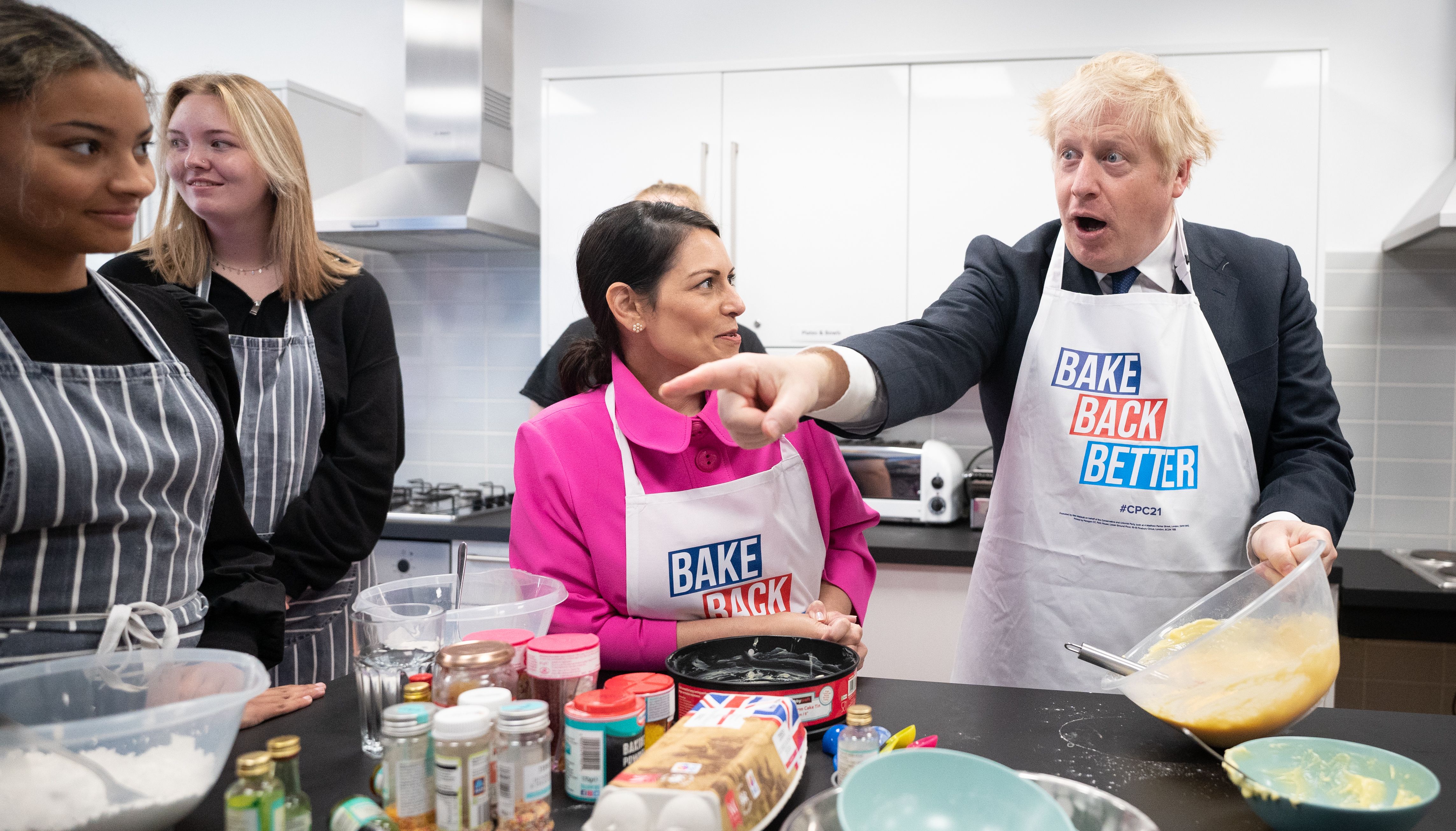 Home Secretary Priti Patel looks on as Prime Minister Boris Johnson tries his hand at baking during a visit to the HideOut Youth Zone, in Manchester.
