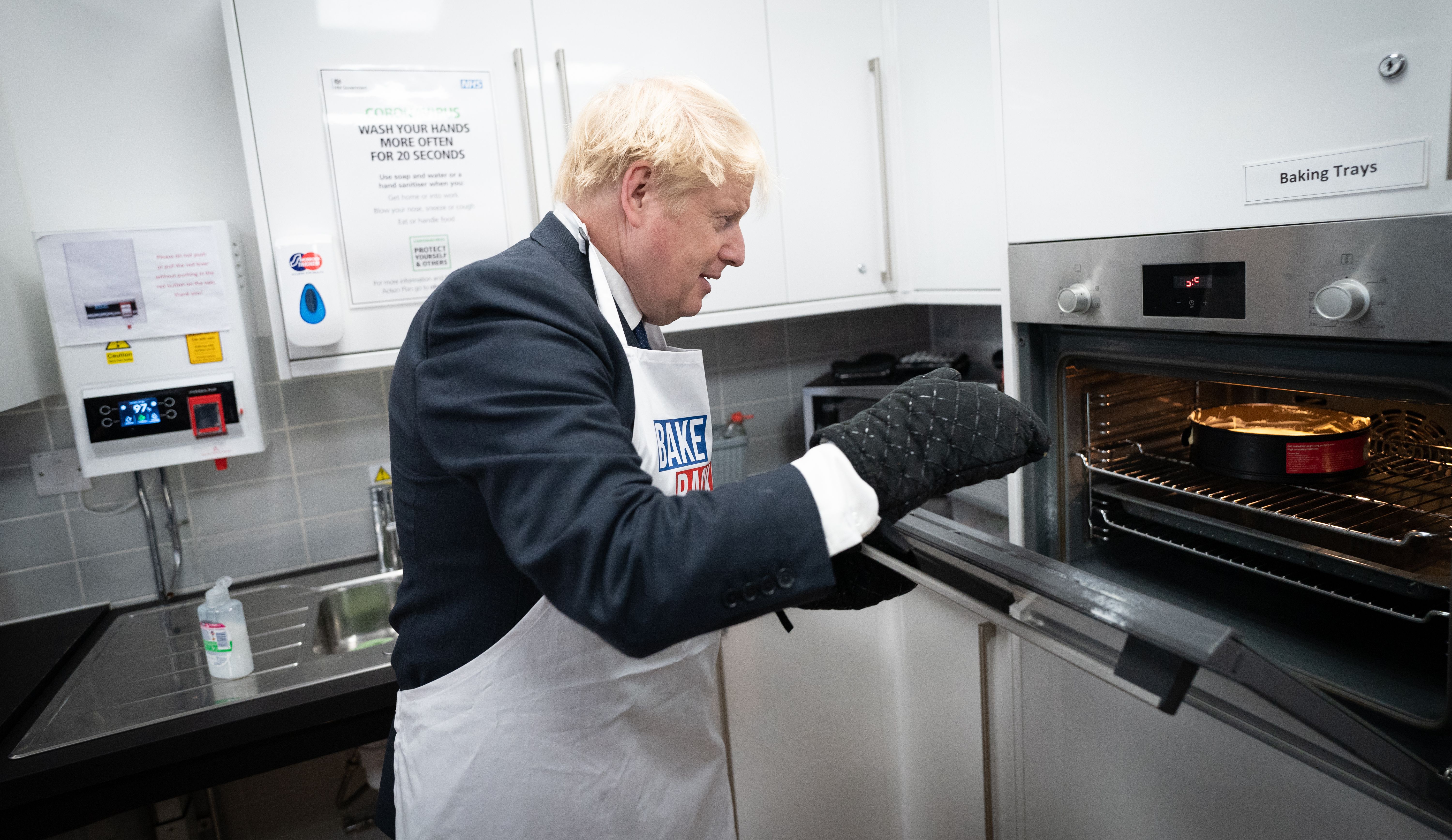 Home Secretary Priti Patel looks on as Prime Minister Boris Johnson tries his hand at baking during a visit to the HideOut Youth Zone.