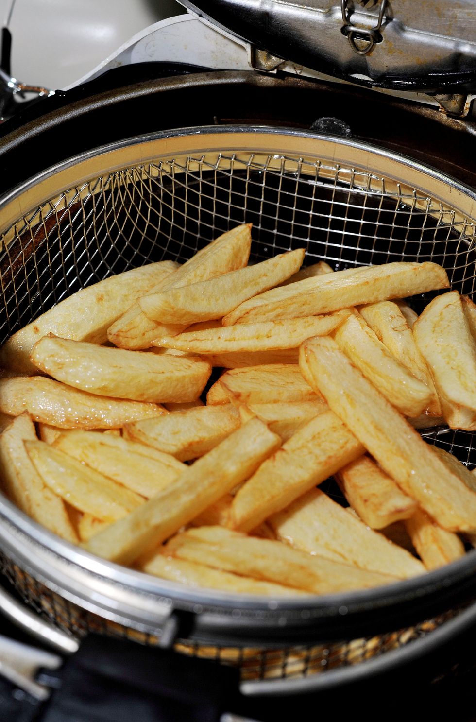 Homemade chips being cooked in a household fat fryer.
