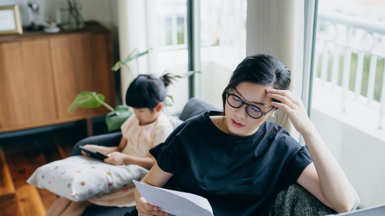 Homeowner looks at mortgage letter with child beside her