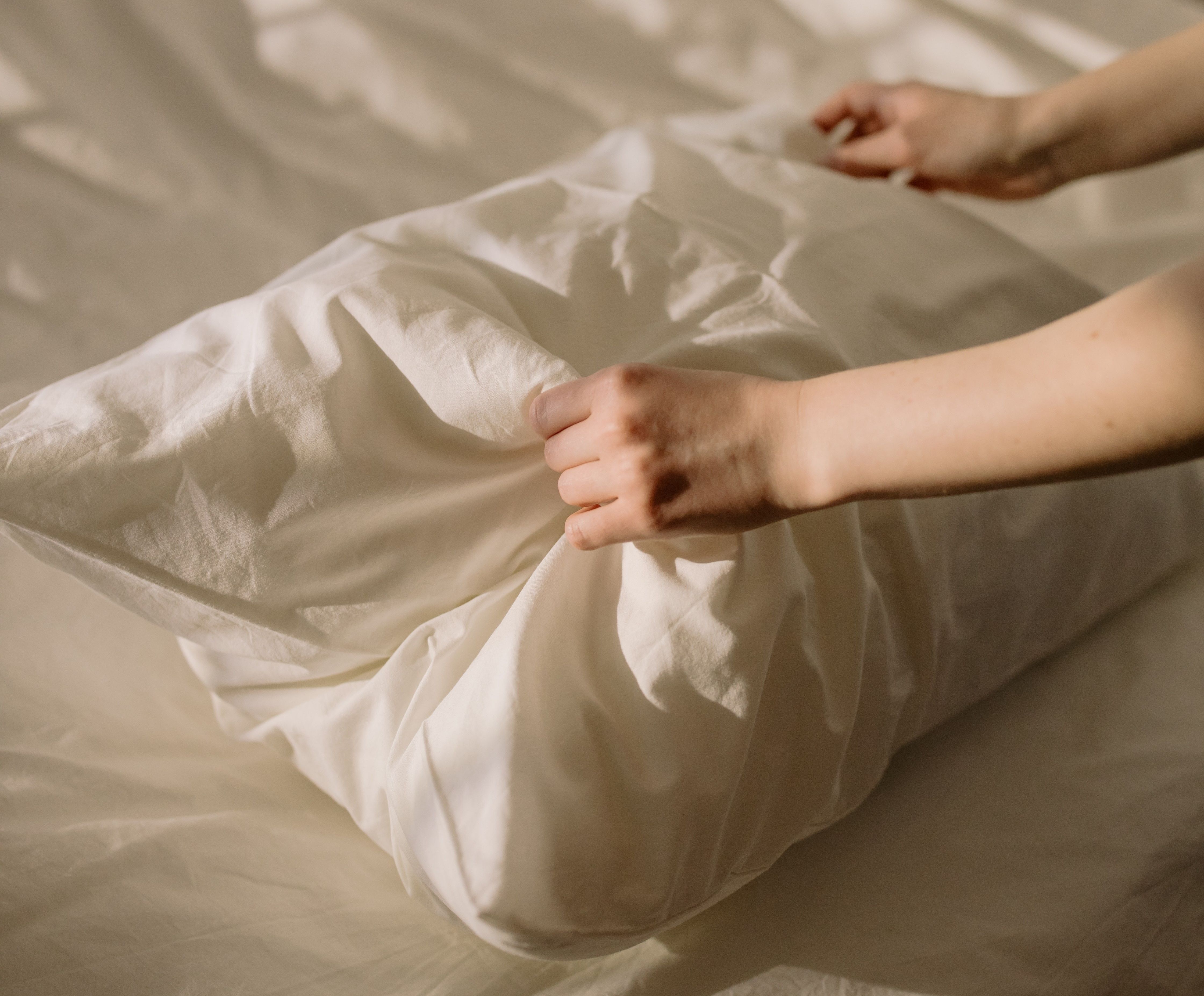 Homeowner making bed with pillow