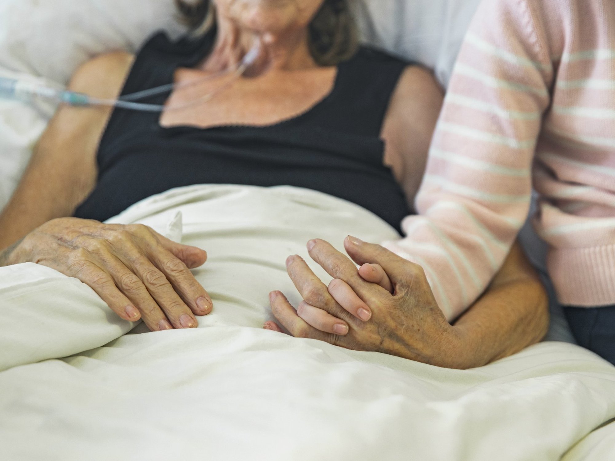 Hospice patient's hand held by loved one
