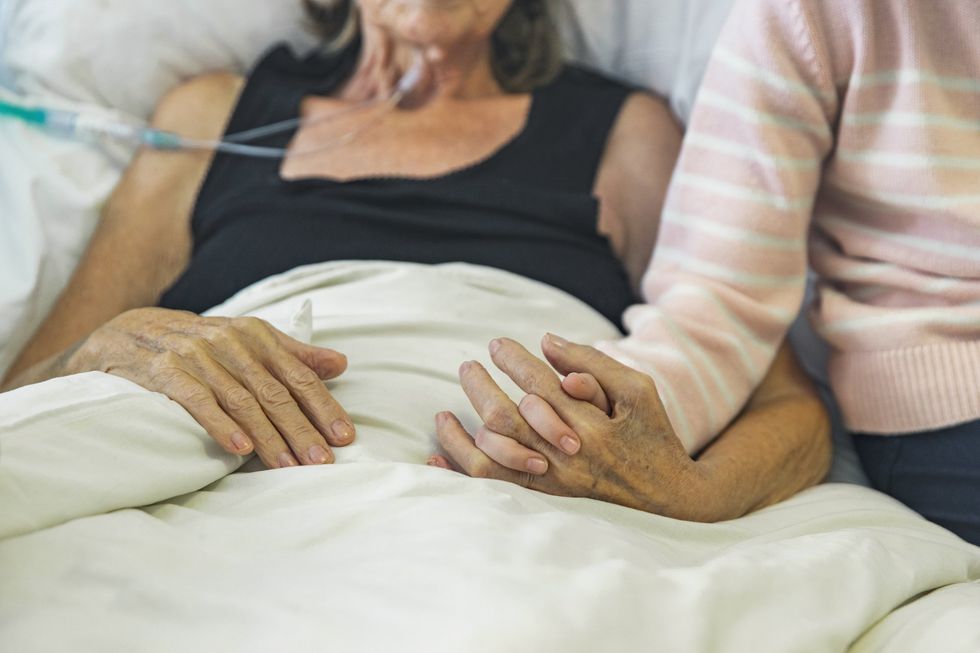Hospice patient's hand held by loved one