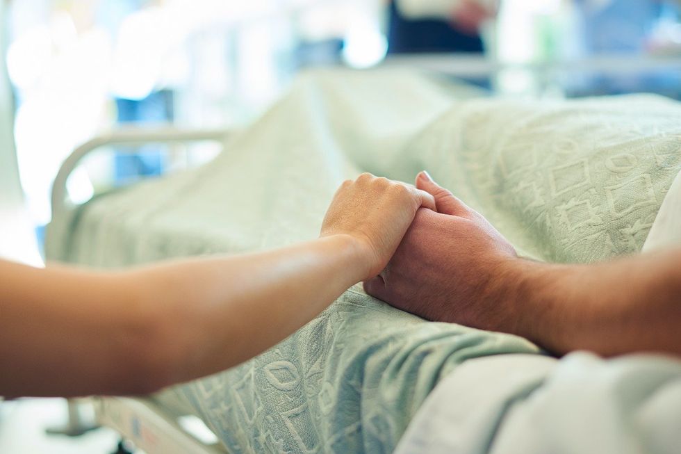 Hospice patient's hand held by loved one