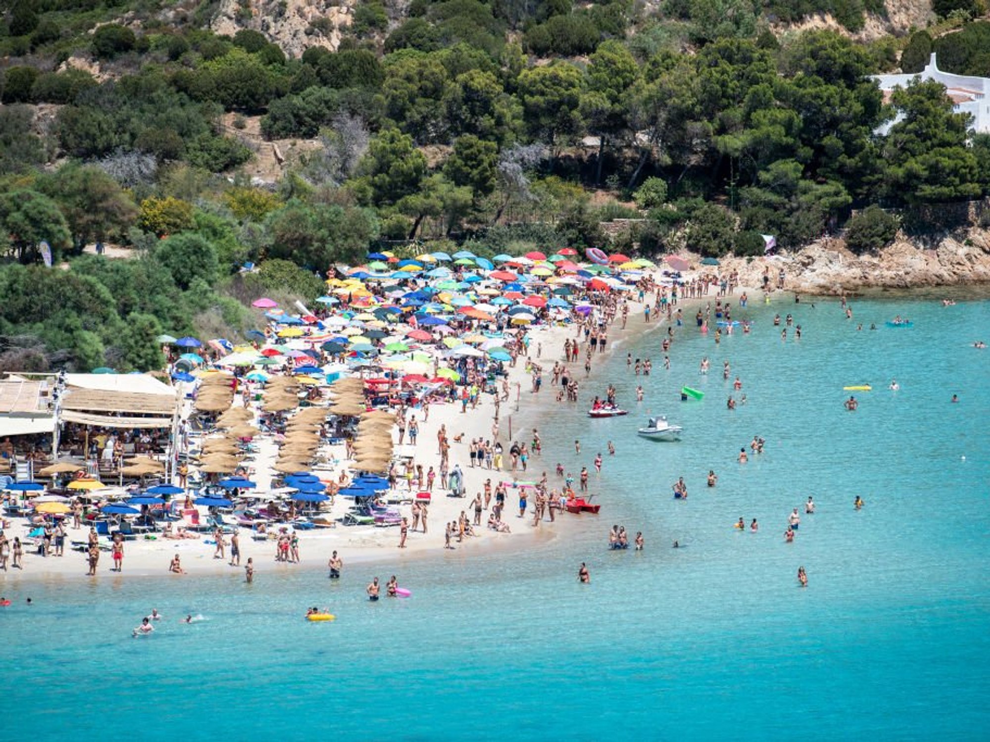 Hundreds of beachgoers with parasols on Punta Molentis beach