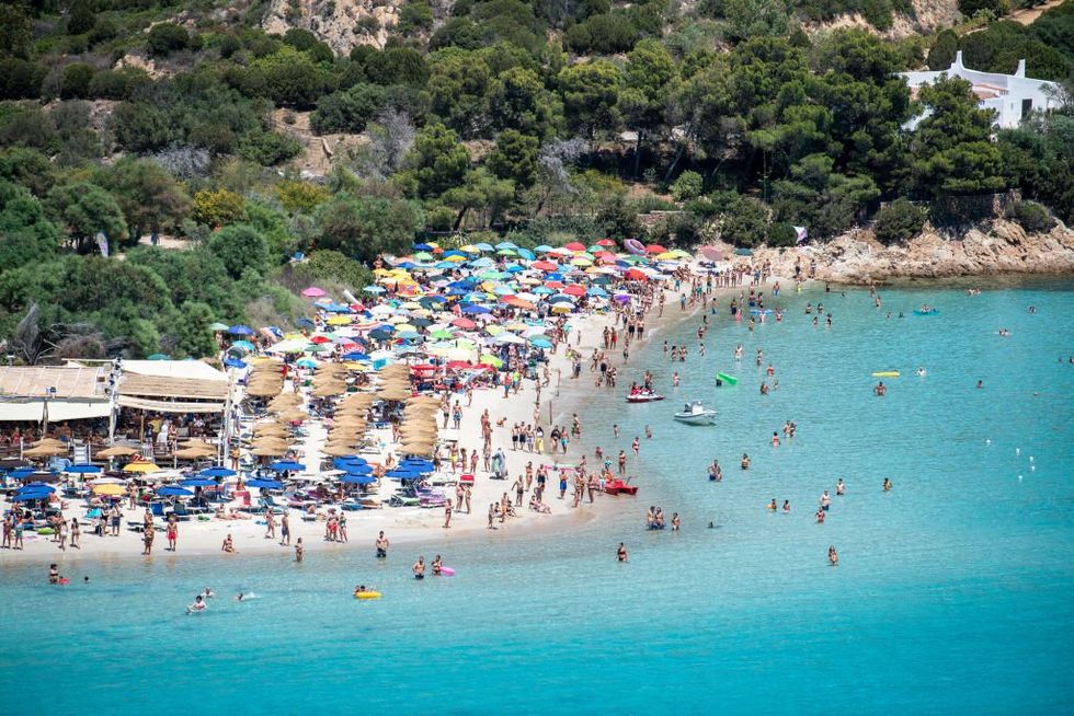 Hundreds of beachgoers with parasols on Punta Molentis beach