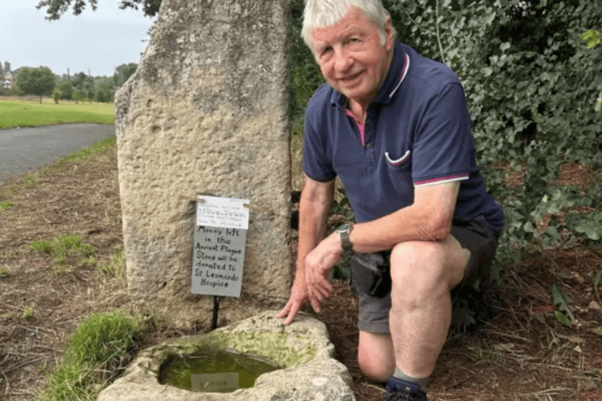 Ian Tomlinson, member of local community conservation group in Yorkshire, kneels next to the Plague Stone located in Hob Moor