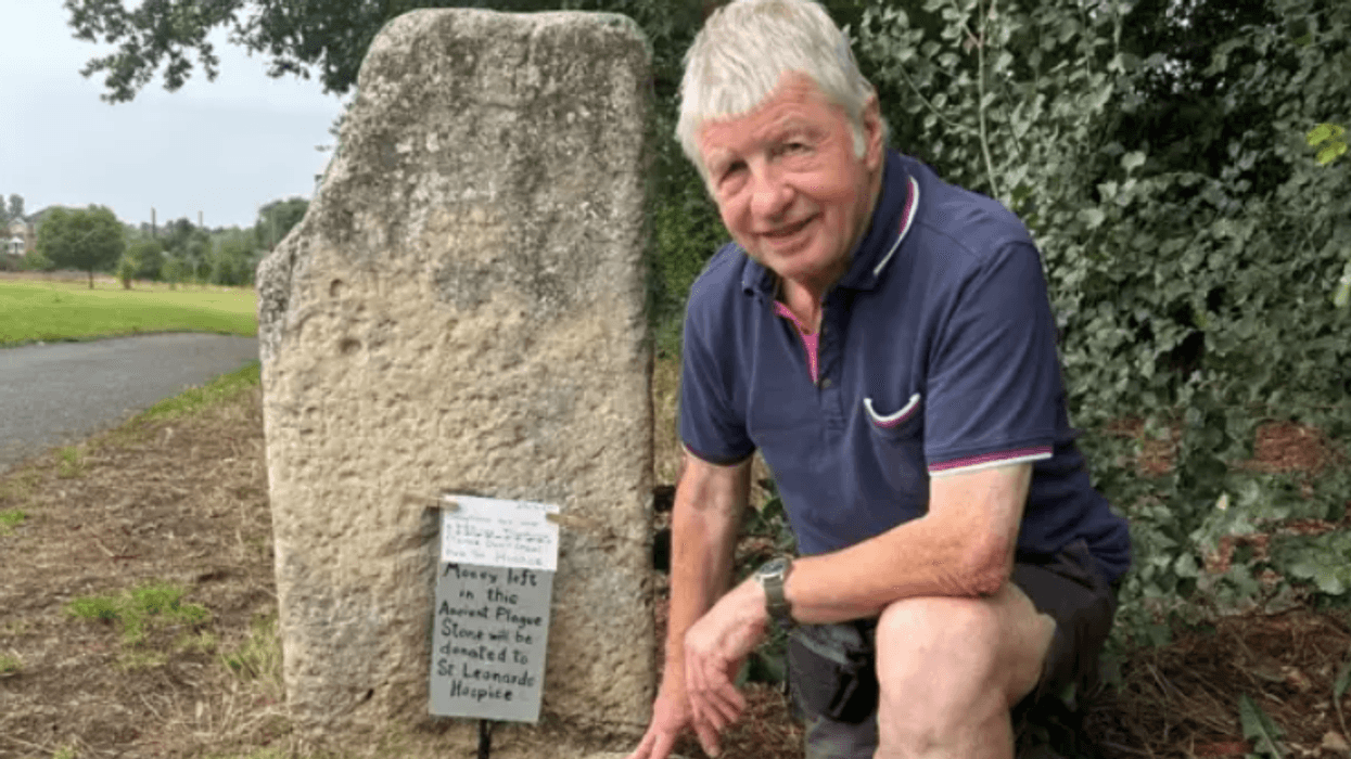 Ian Tomlinson, member of local community conservation group in Yorkshire, kneels next to the Plague Stone located in Hob Moor