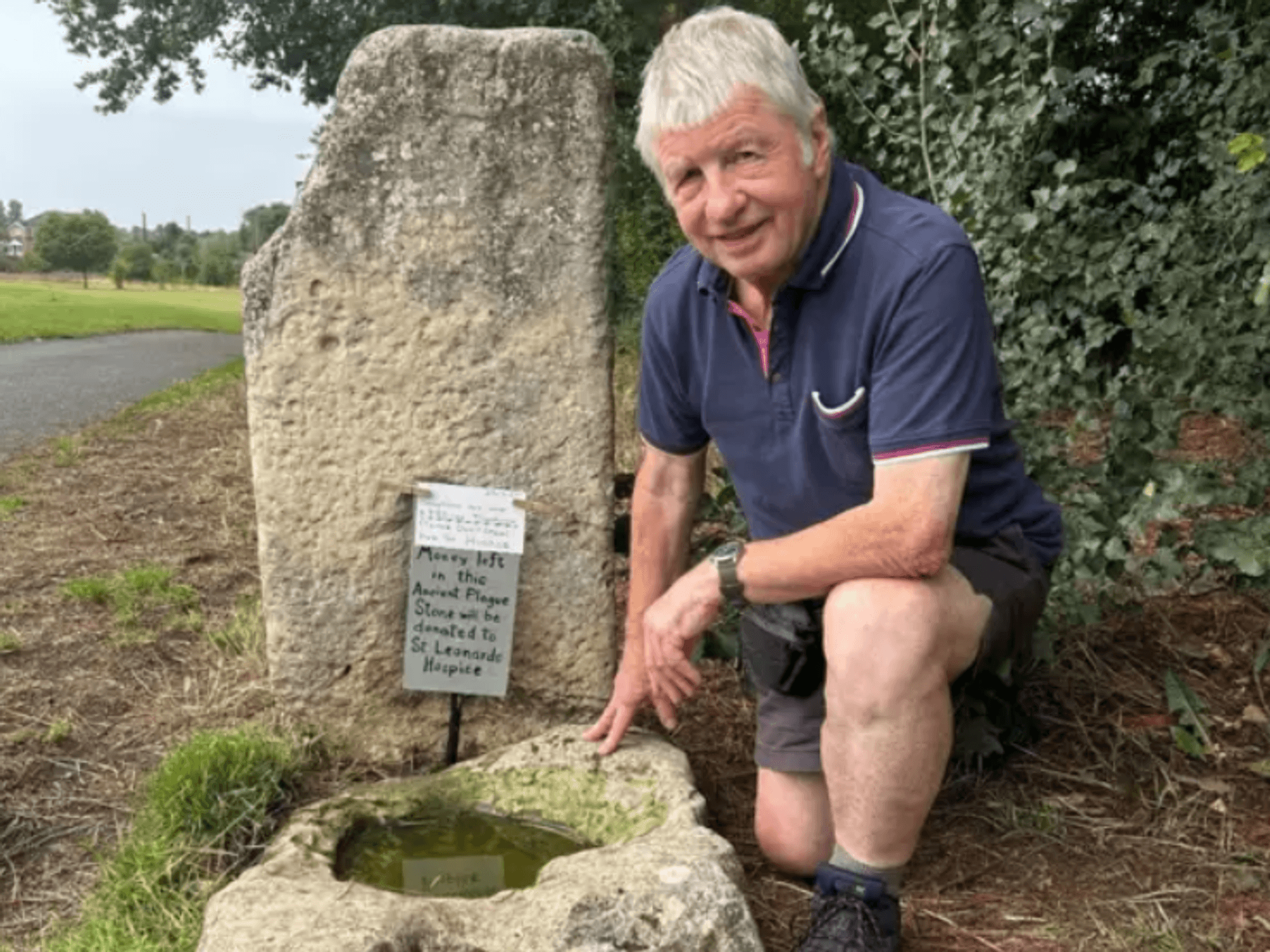 Ian Tomlinson, member of local community conservation group in Yorkshire, kneels next to the Plague Stone located in Hob Moor