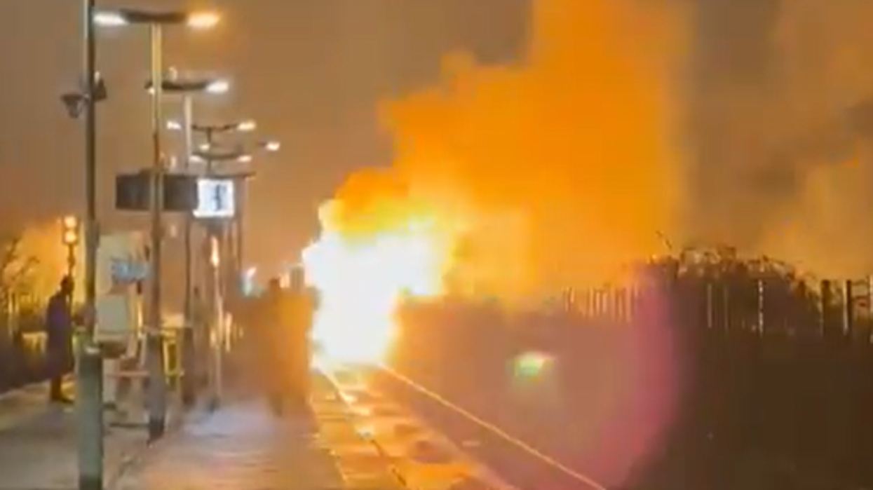 Flames erupt and black smoke fills night sky in huge blaze on train line