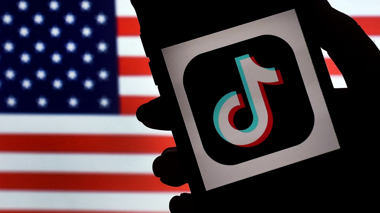 In this photo illustration, the social media application logo, TikTok is displayed on the screen of an iPhone on an American flag background