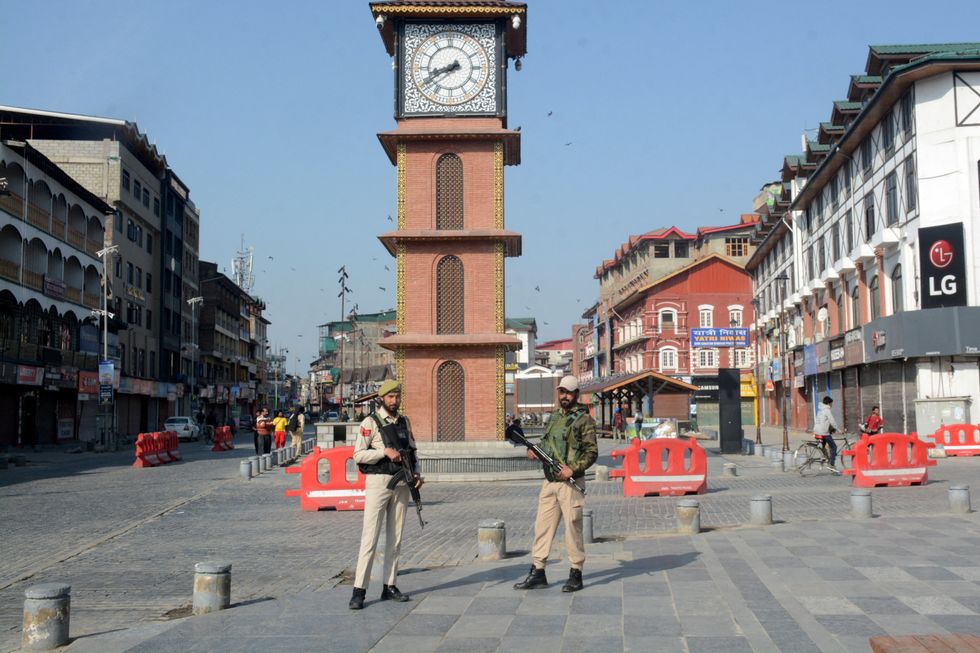 Indian police officers stand guard in front of clock tower following a suspected militant attack near south Kashmir's scenic Pahalgam