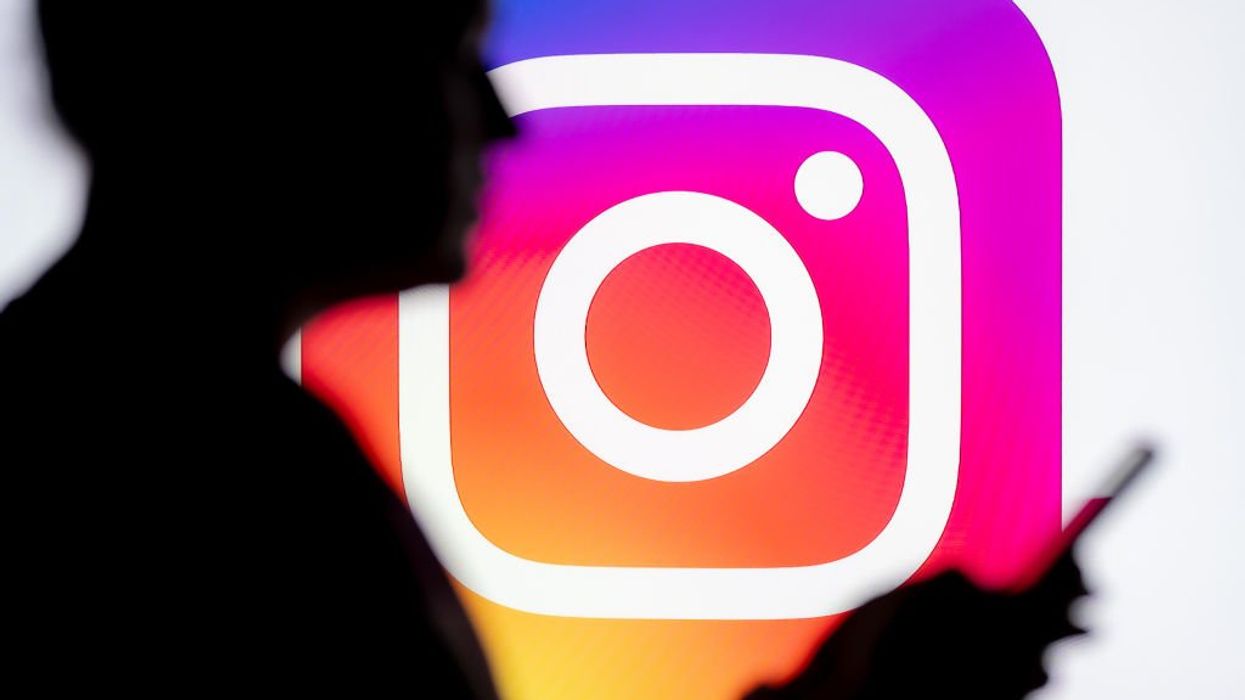 Instagram logo with shadow of person in front holding phone