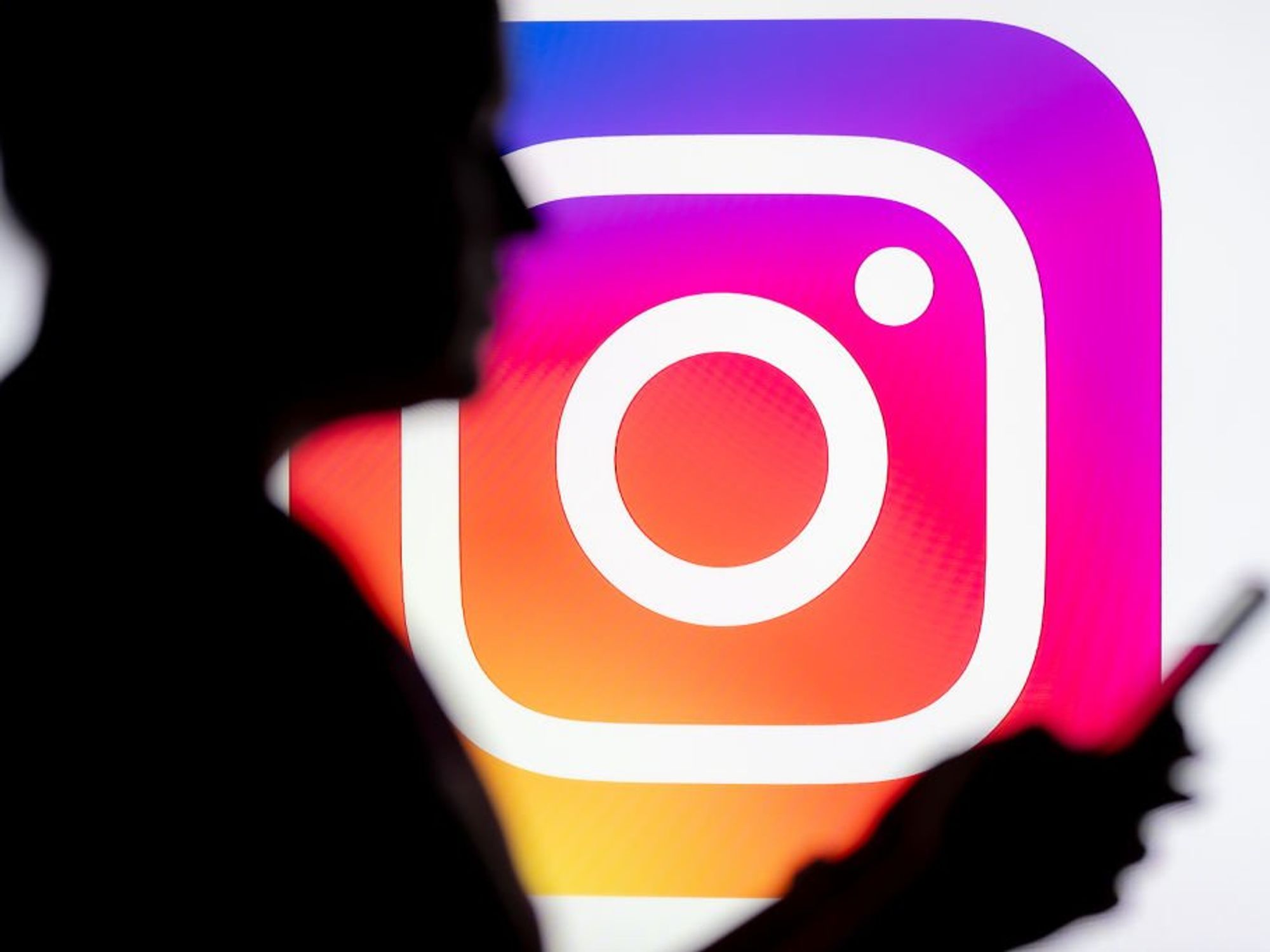 Instagram logo with shadow of person in front holding phone