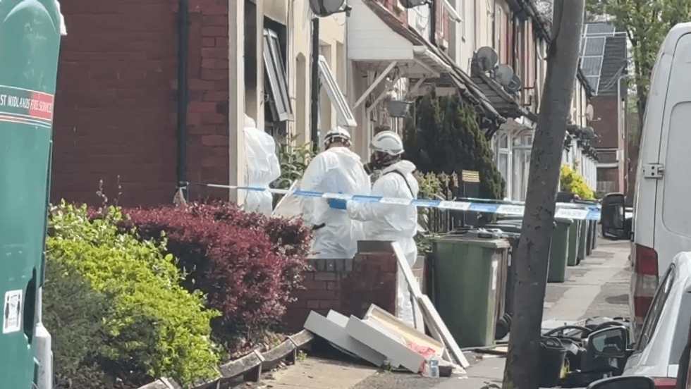 Investigators entering property with a police cordon round it