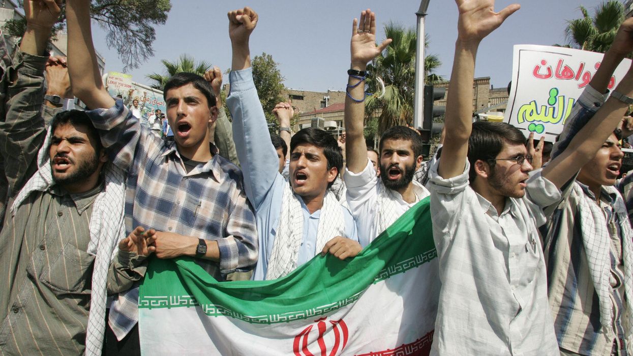Iranian demonstrators holding their national flag chant slogans against US and Britain during a demonstration in front of the British embassy in Tehran