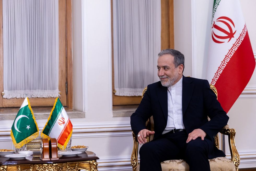 Iranian Foreign Minister Abbas Araghchi sitting with an Iranian flag behind him