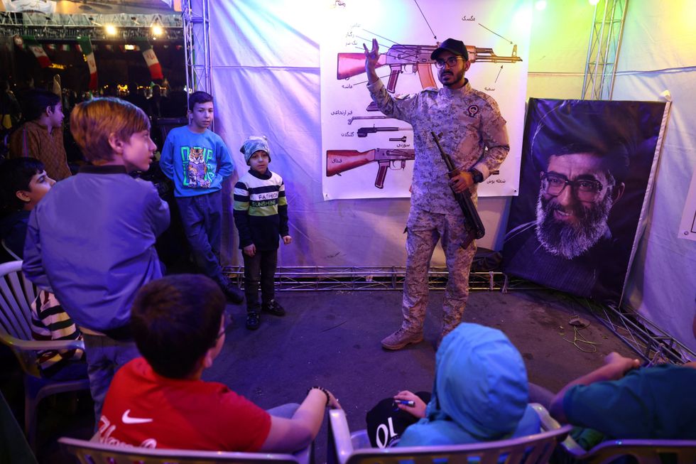 Iranian military member instructs children on how to use assault weapons