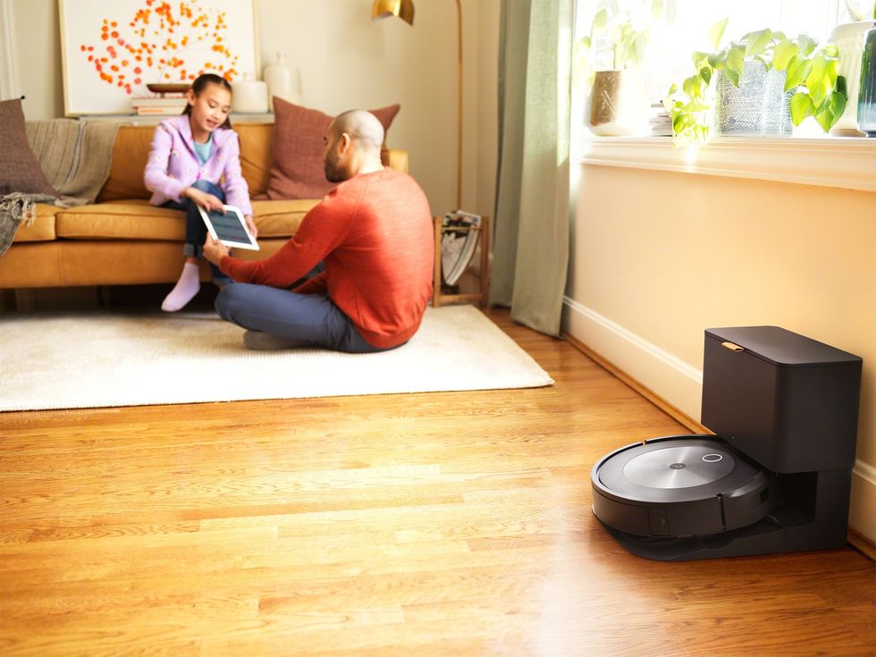 irobot roomba in its charging stand with a father and son playing in the background