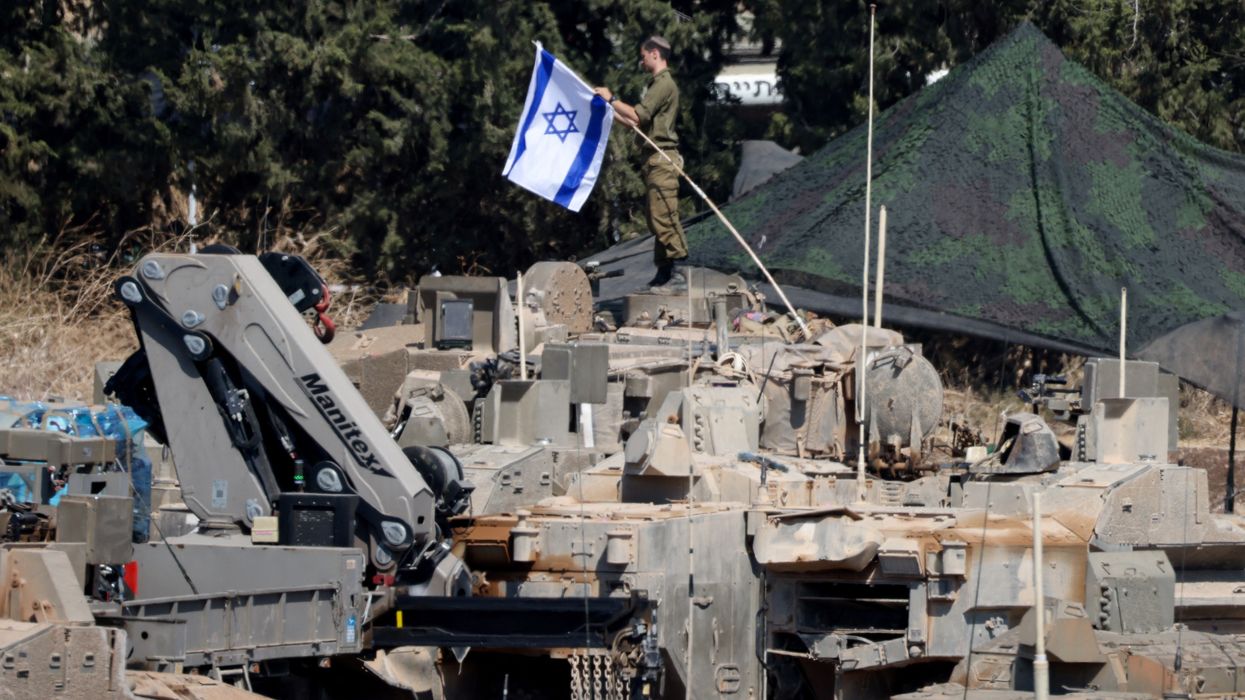 Israeli members of the military stand next to armoured vehicles