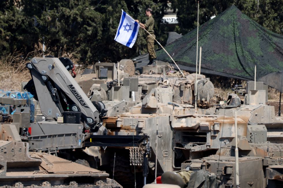 Israeli members of the military stand next to armoured vehicles
