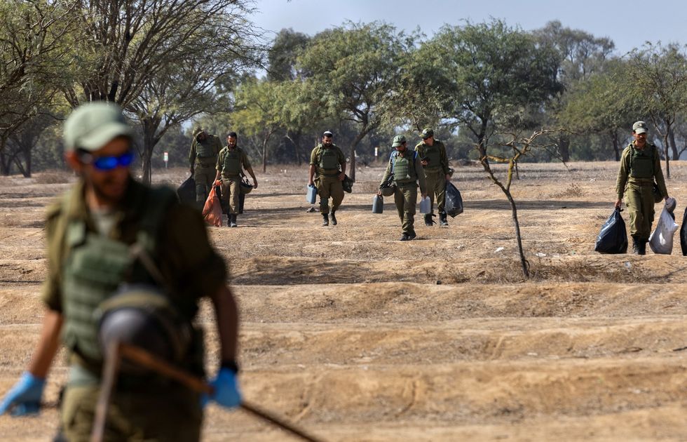 Israeli soldiers clean debris and personal items left behind at the site of the surprise attack launched by Hamas