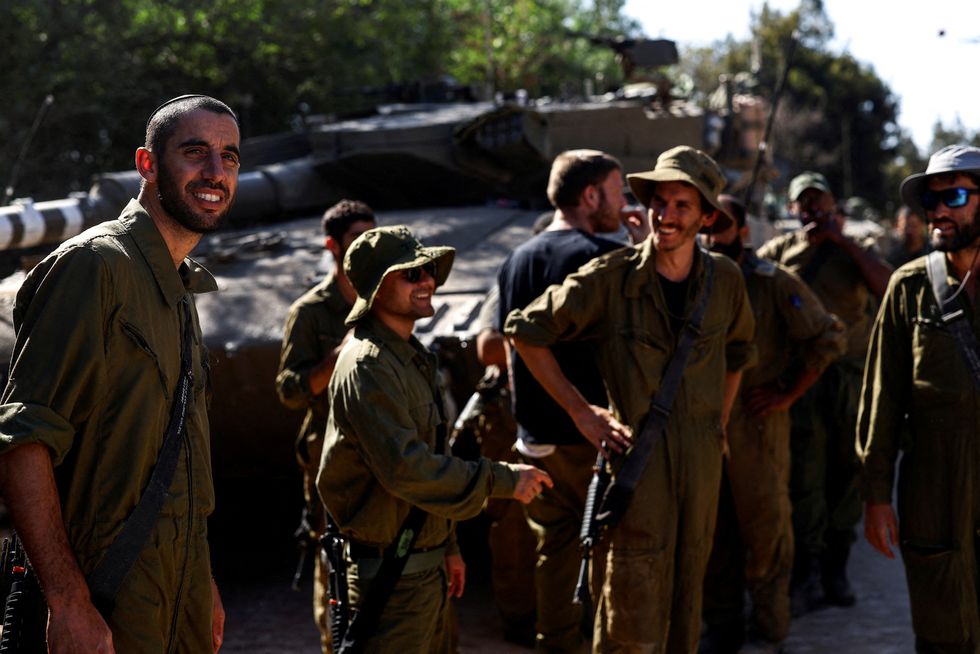 Israeli soldiers gather by military vehicles at Israel's border with Lebanon