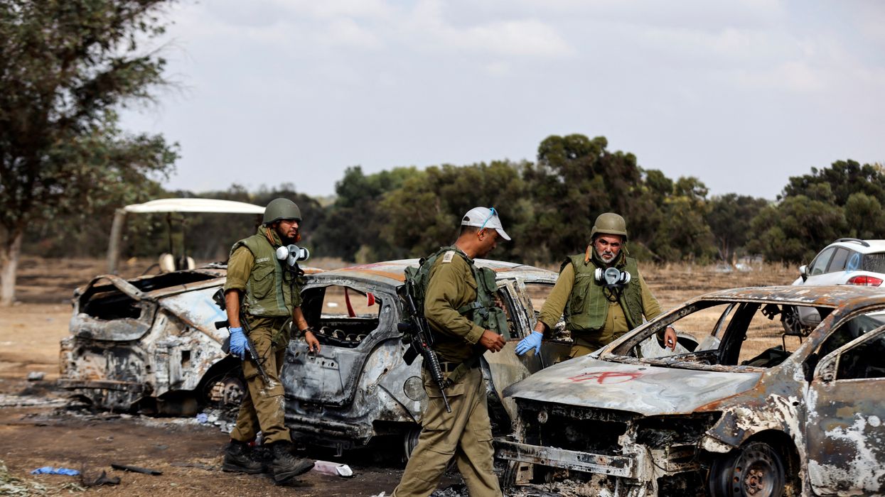 Israeli soldiers inspect the burnt cars of festival-goers at the site of an attack on the Nova Festival by Hamas