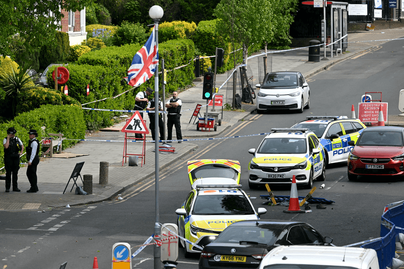 Items, including clothes and trainers, are pictured strewn in the road in front of a Police car (R), inside a Police cordon on Golders Green Road, in the Golders Green neighbourhood of north London, on April 29, 2026, after two people were stabbed, and a suspect arrested.