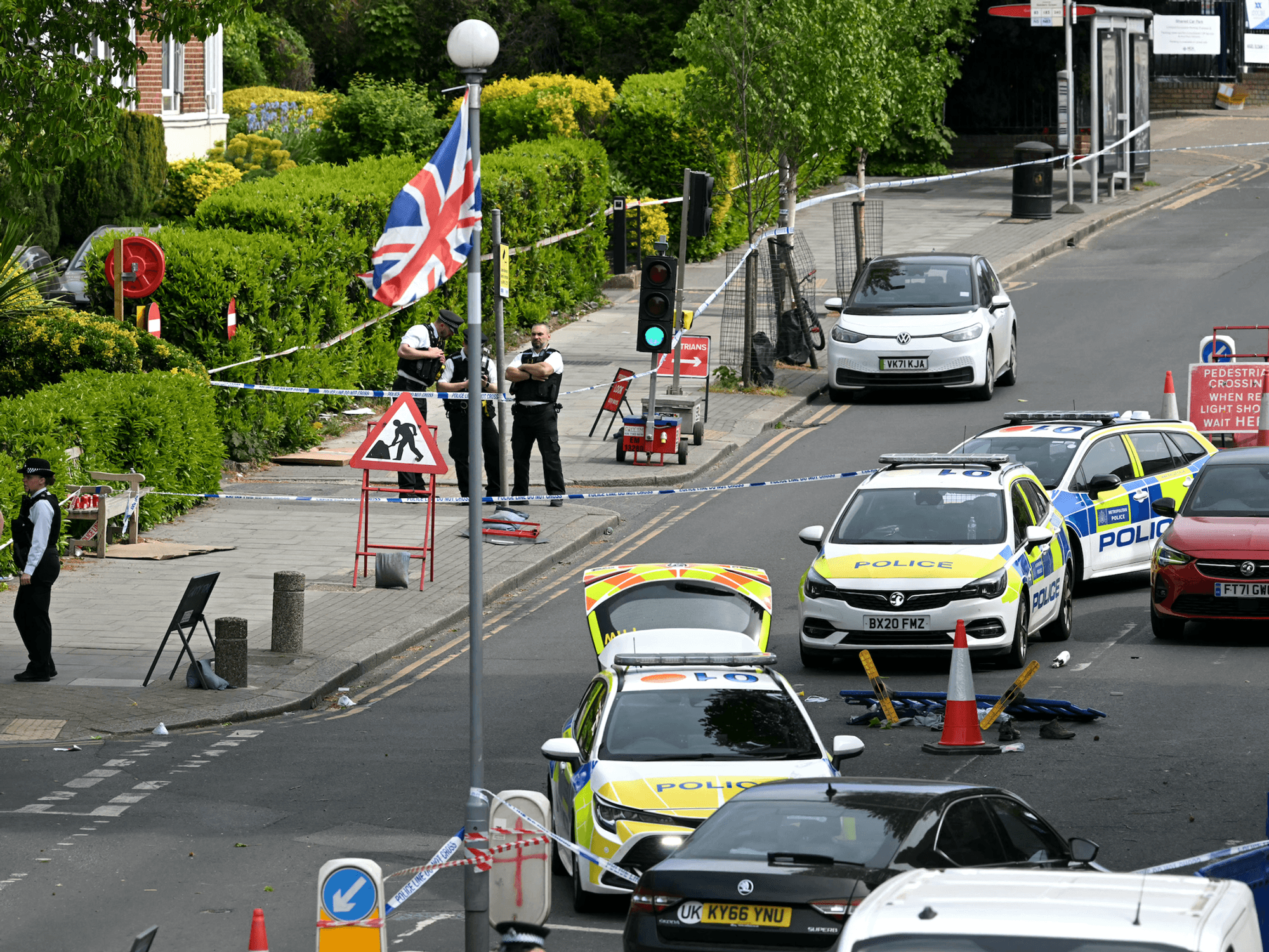 Items, including clothes and trainers, are pictured strewn in the road in front of a Police car (R), inside a Police cordon on Golders Green Road, in the Golders Green neighbourhood of north London, on April 29, 2026, after two people were stabbed, and a suspect arrested.