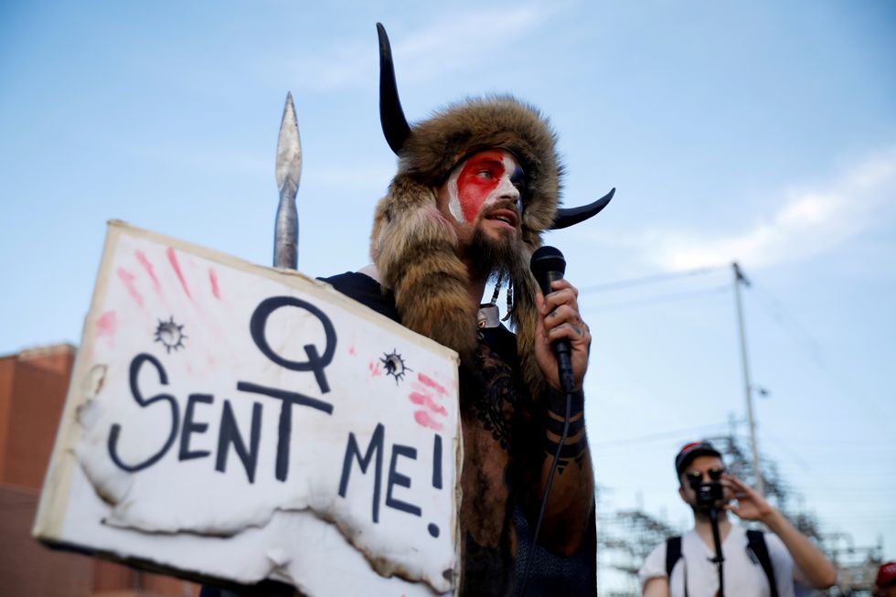 Jacob Chansley, holding a sign referencing QAnon, speaks as supporters of U.S. President Donald Trump gather to protest about the early results of the 2020 presidential election, in front of the Maricopa County Tabulation and Election Center (MCTEC), in Phoenix.
