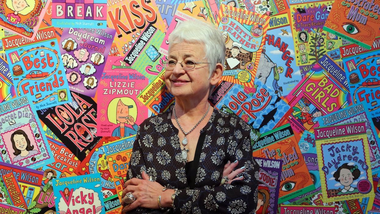 Jacqueline Wilson in front of a backdrop featuring her books