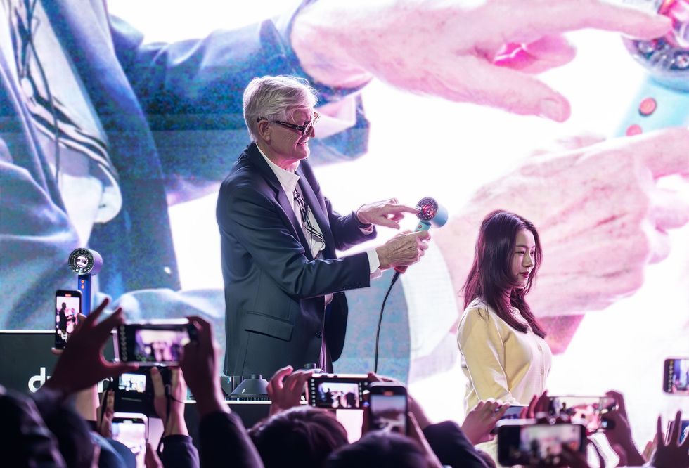 james dyson on stage with a model showing the led indicator inside the dyson supersonic nural